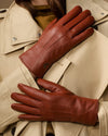 Cognac brown leather gloves laid flat with stitched seams and long cuffs