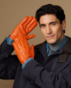Men’s orange leather gloves with blue lining cuff, hand posed forward