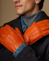 Orange leather gloves with blue cuff lining, close-up on joined hands
