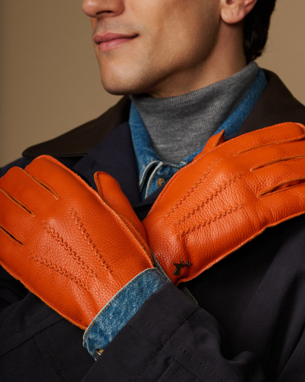 Orange leather gloves with blue cuff lining, close-up on joined hands