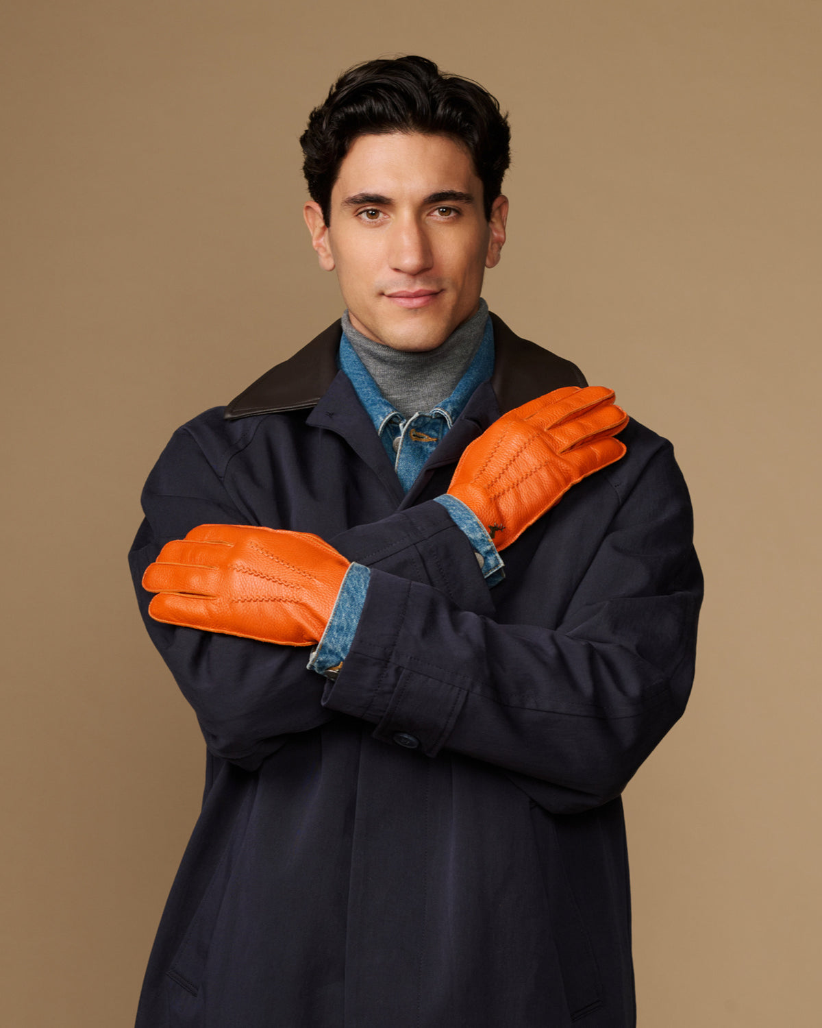 Men’s orange leather gloves with blue lining cuff, arms crossed