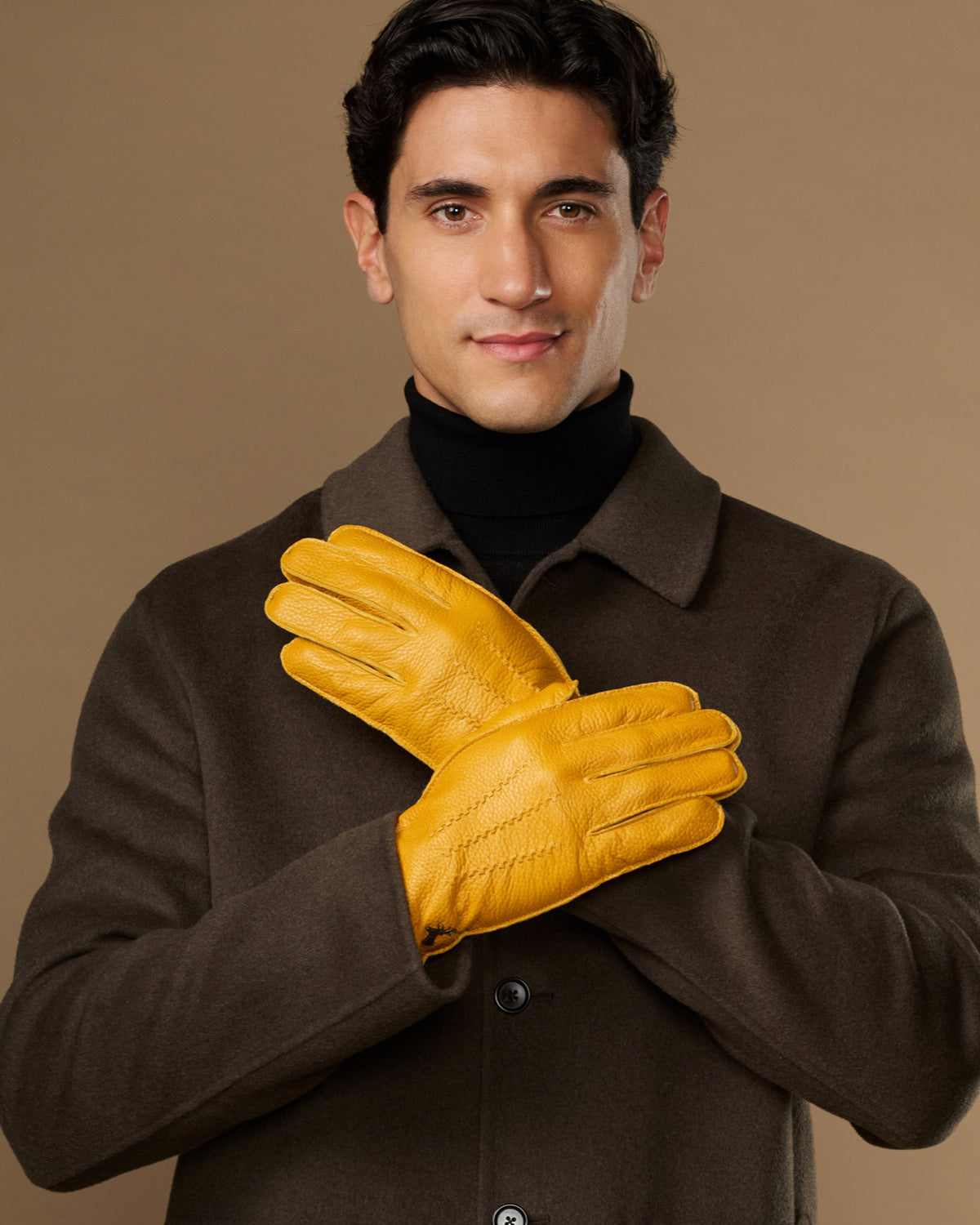 Yellow leather gloves on model, two gloves clasped at chest