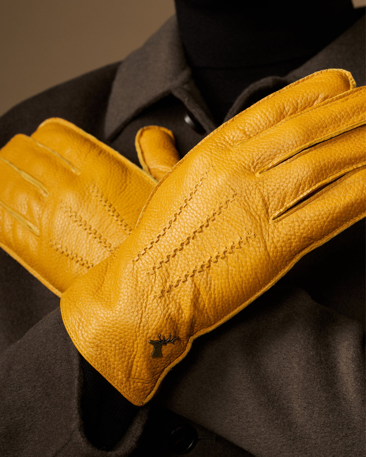 Yellow leather gloves held up close-up, visible stitched seams and texture