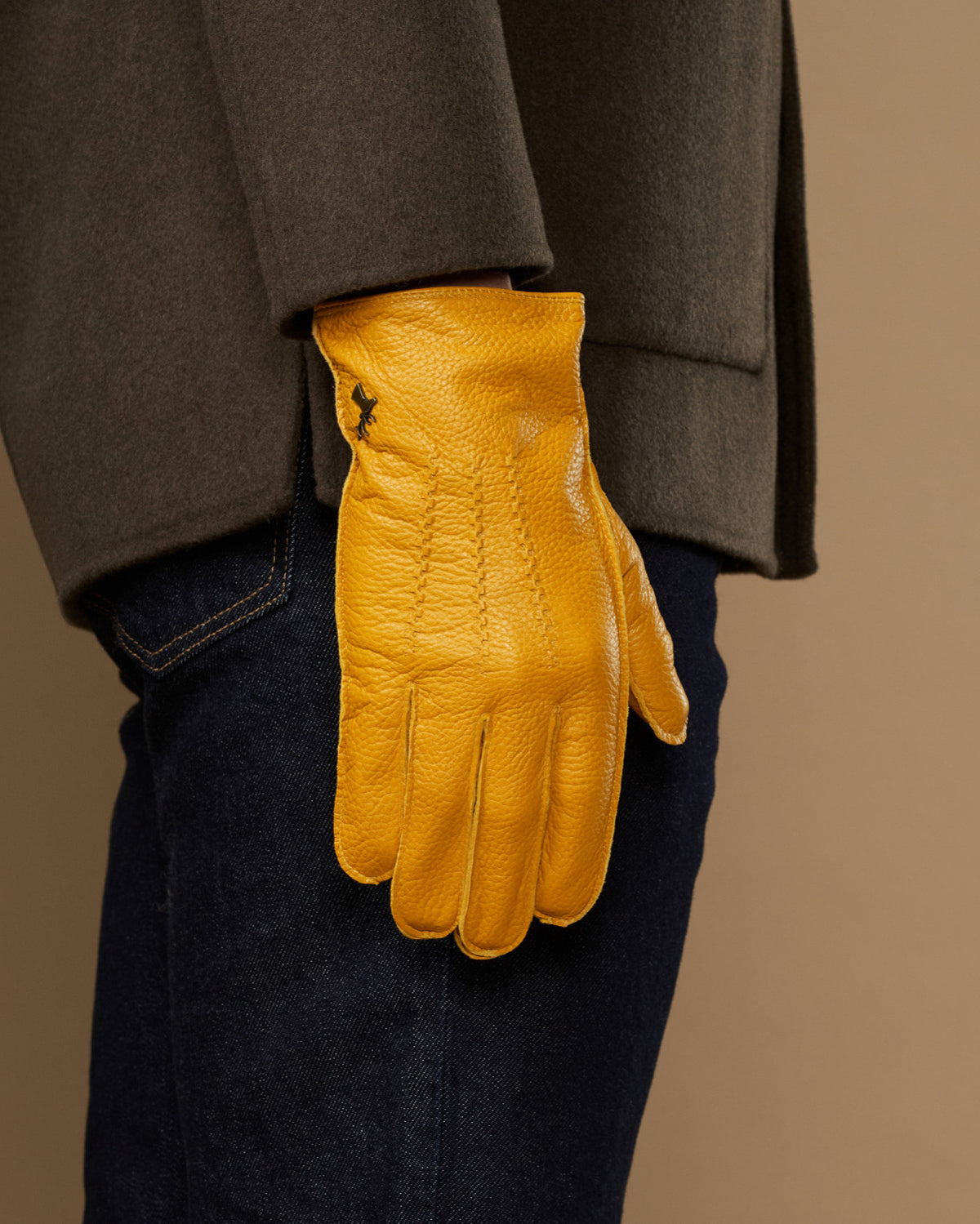 Yellow leather gloves on model, cuffed pair hanging at side