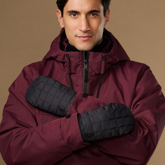 Black quilted waterproof mittens with long cuffs, modeled on crossed hands.