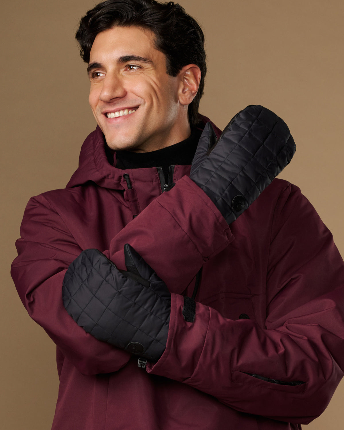 Pair of black quilted mittens shown from the back and side.