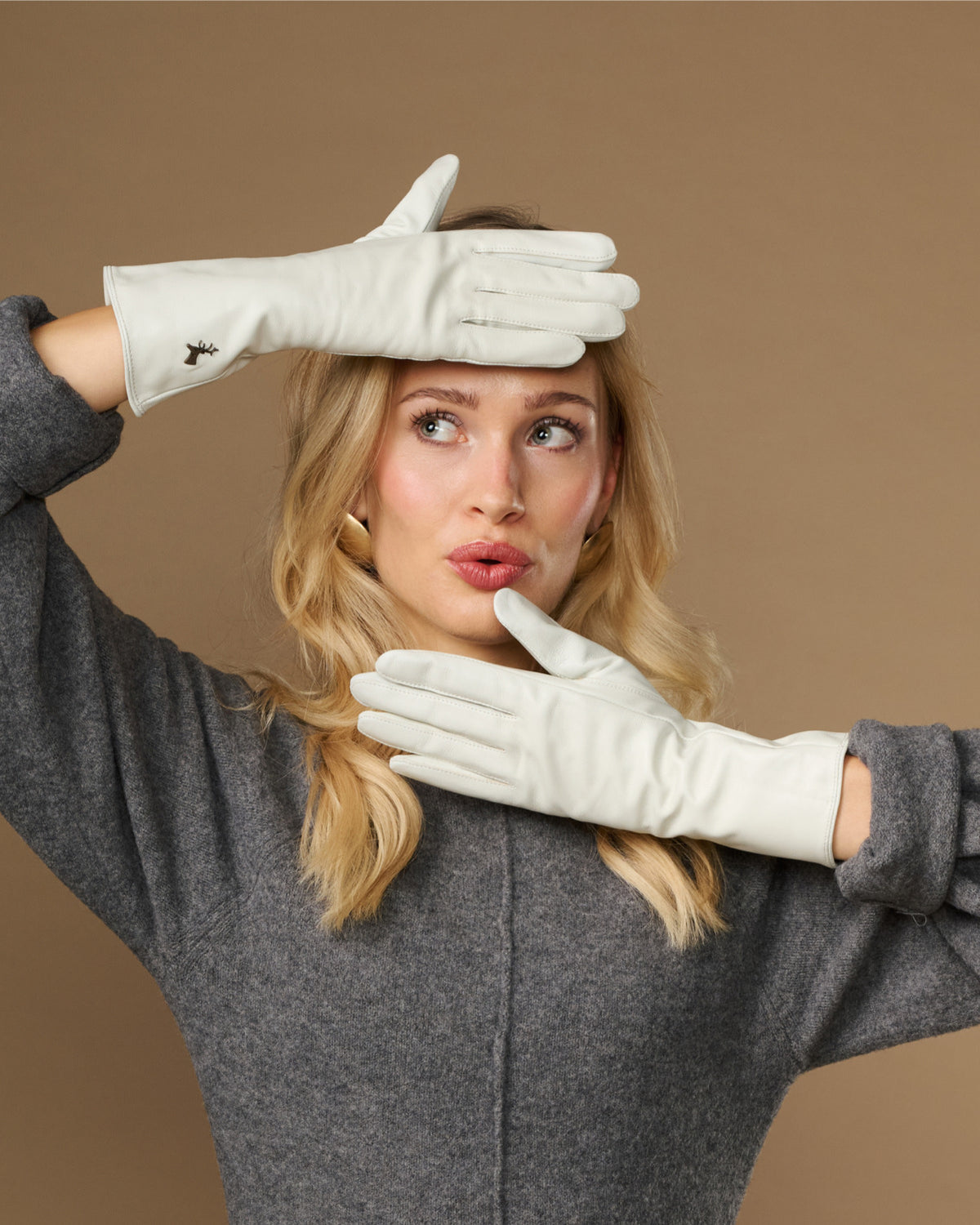 White long leather gloves held up, touchscreen fingertips visible