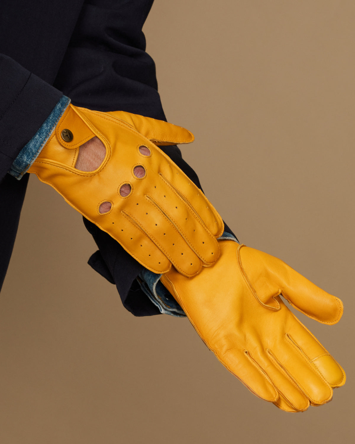 Men's yellow lambskin glove on wrist, stitched finger panels and buttoned cuff