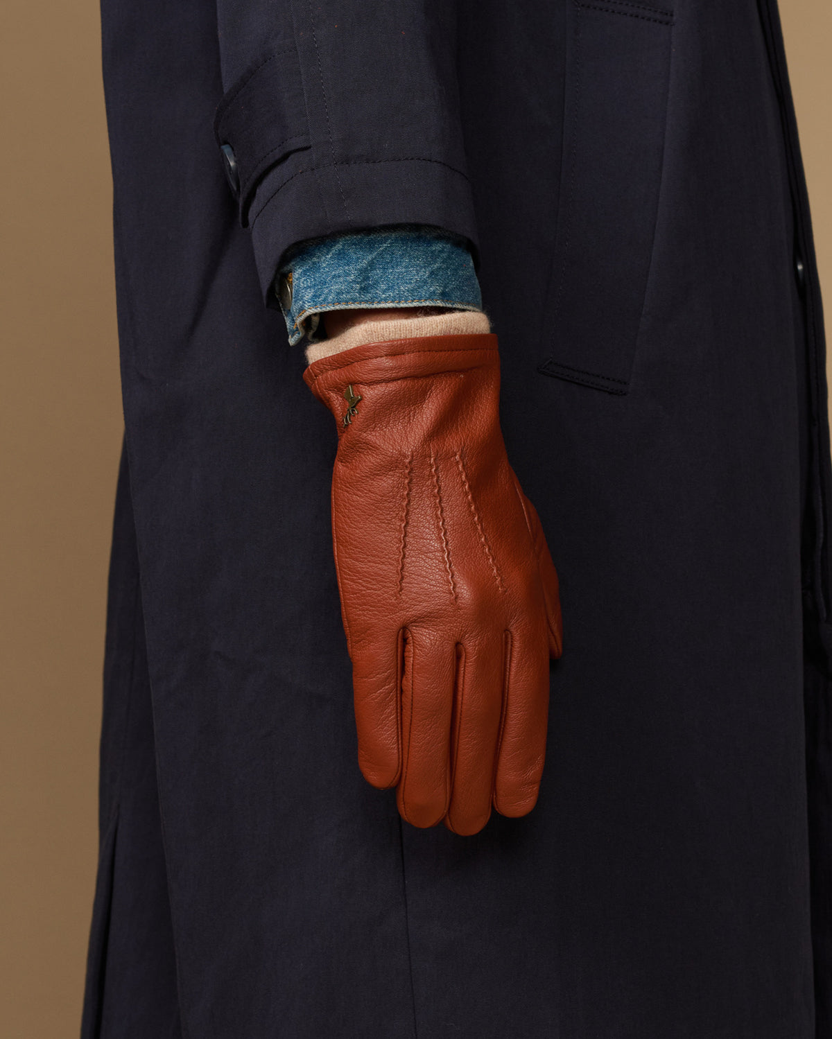 Cognac leather glove cuff with blue wool lining on dark sleeve