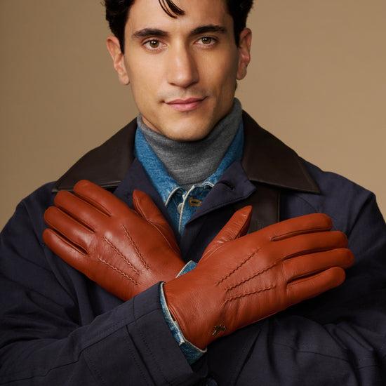 Men's cognac goatskin gloves with blue lambswool lining, arms crossed