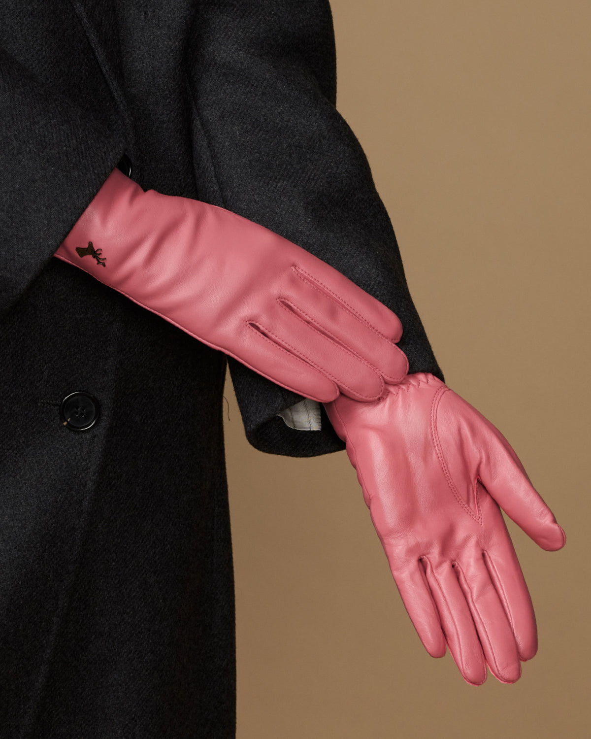 Women’s pink leather glove detail with stitched seams and small logo on wrist