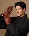 Cognac leather gloves with fleece-lined cuffs, model holding one glove raised