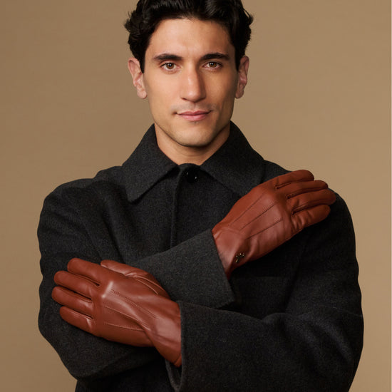 Cognac leather gloves with fleece-lined cuffs, arms crossed with gloves on