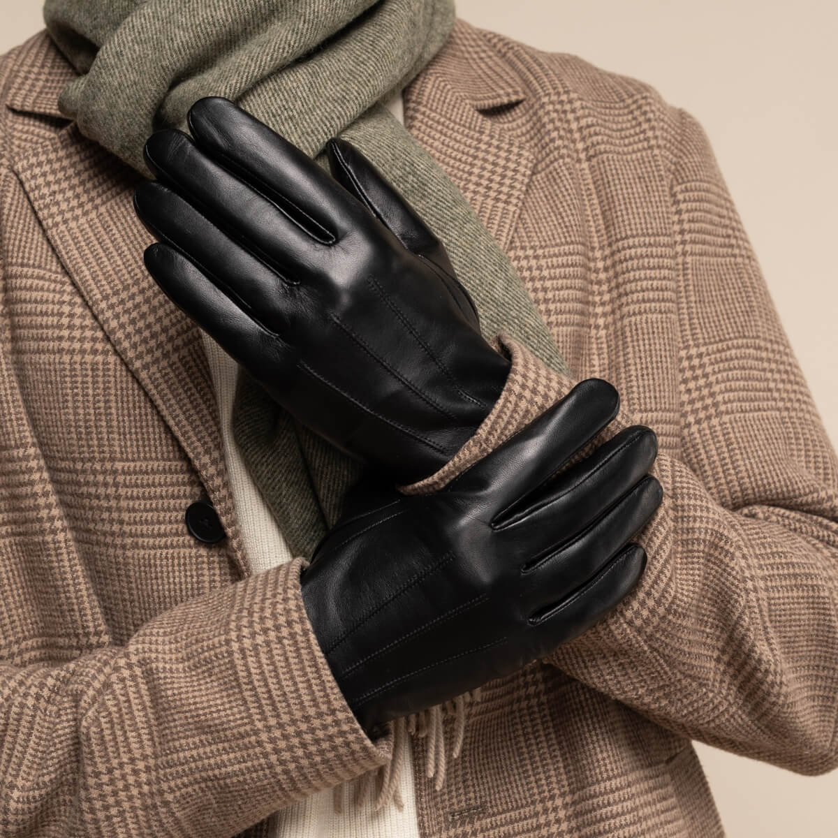 Pair of black leather gloves with curved knuckle panel stitching