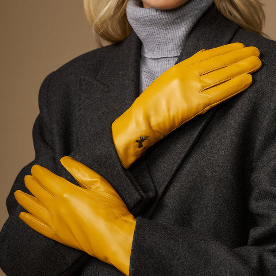 Yellow lambskin leather gloves with stitched fingers and small emblem on the wrist cuff