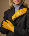 Yellow lambskin leather gloves with stitched fingers and small emblem on the wrist cuff