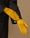 Close-up of yellow leather gloves showing stitched seams and shaped fingertips