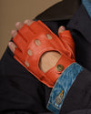 Men's orange fingerless lambskin driving gloves with perforated finger details and badge snap