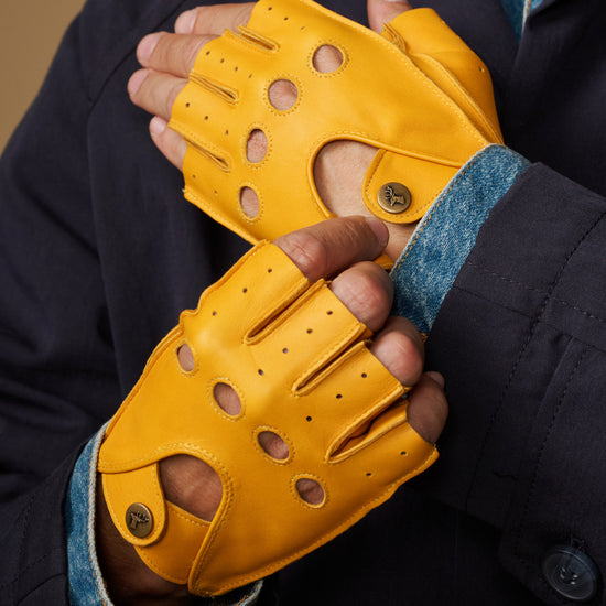 Yellow fingerless lambskin driving gloves with perforated panels and snap strap