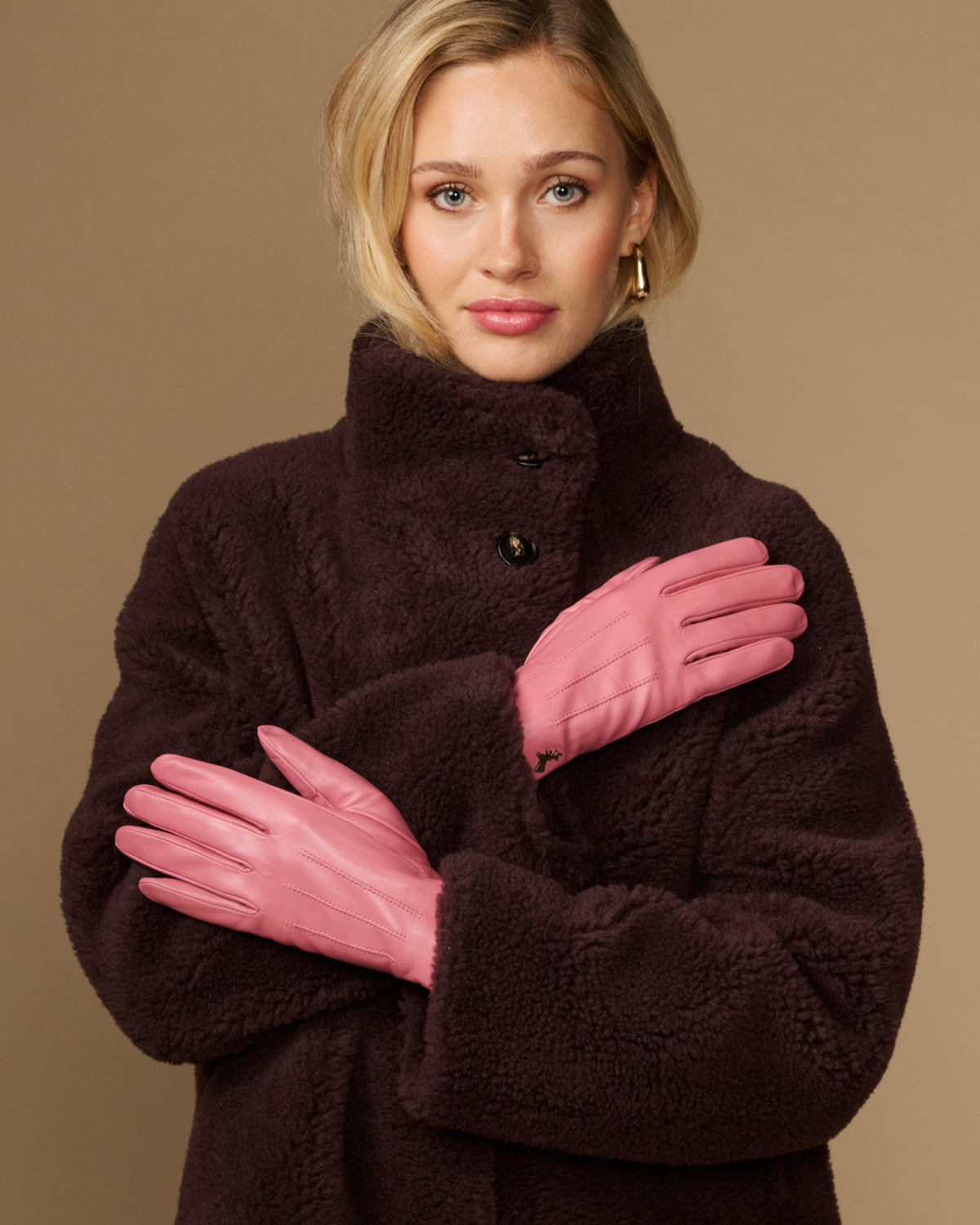 Pink leather gloves with dark fleece lining, buttoned cuff detail