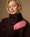 Pink leather gloves with dark fleece sherpa lining, one hand across chest