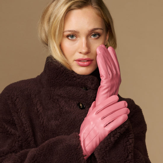 Pink leather gloves with dark fleece lining, hands held near face
