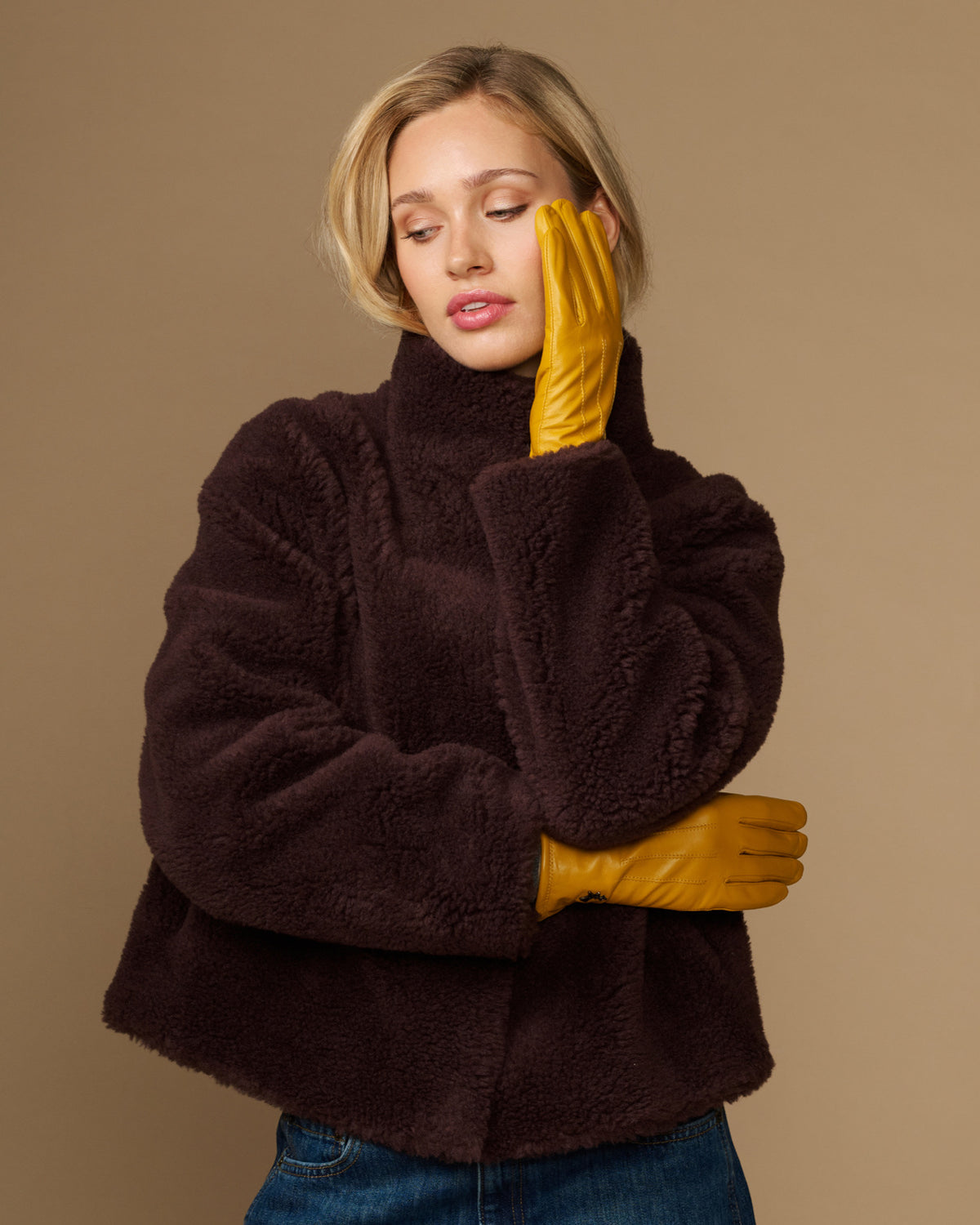 Yellow leather gloves with fleece-lined cuff, arms crossed while wearing a coat