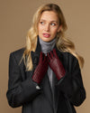 Women's black leather gloves with red-and-black checkered lining, arms crossed
