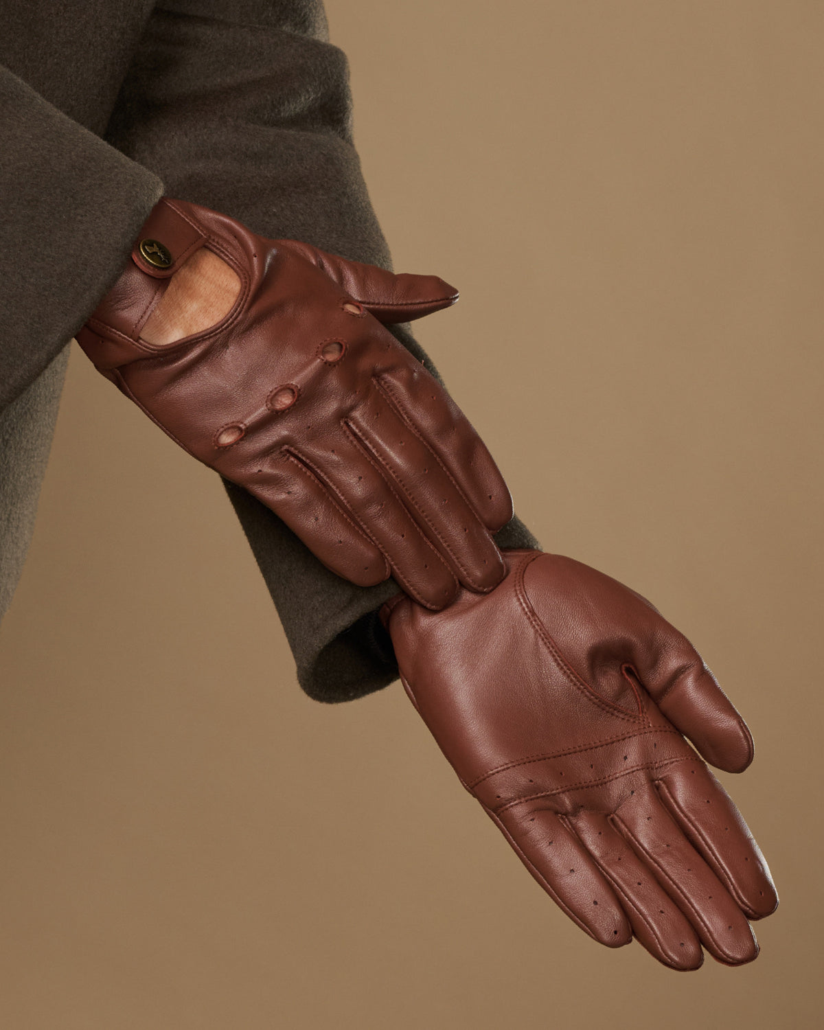 Brown leather driving gloves with stitched seams and fitted knuckle panels
