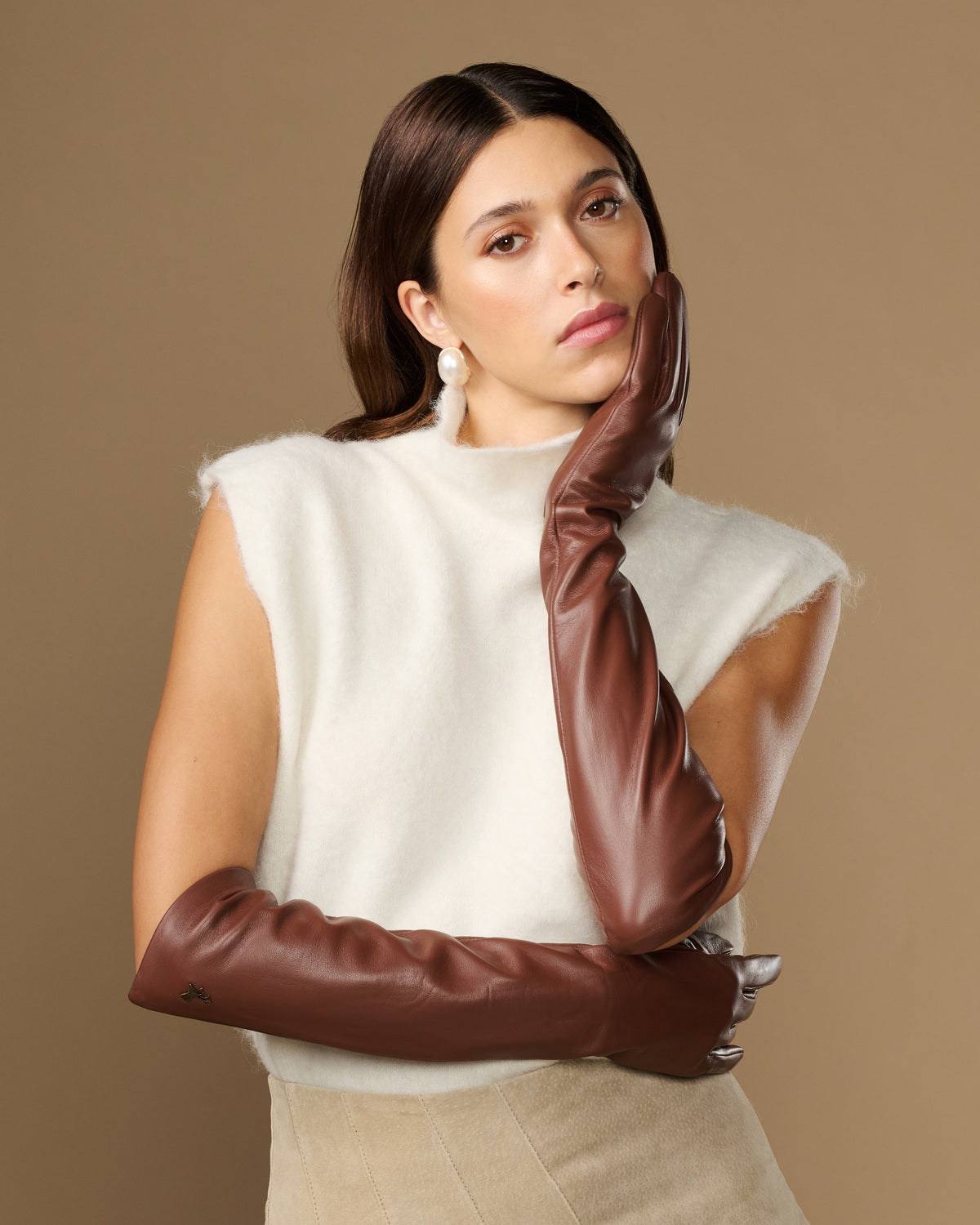 Women’s brown leather elbow gloves with smooth finish, worn across chest.