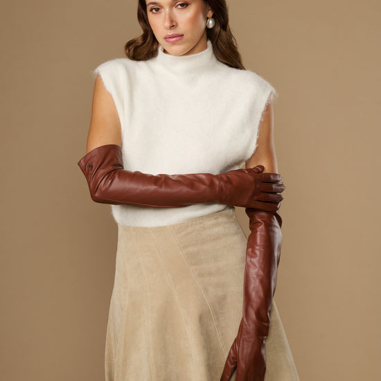 Chestnut brown leather opera gloves with long fit, one glove holding the other cuff