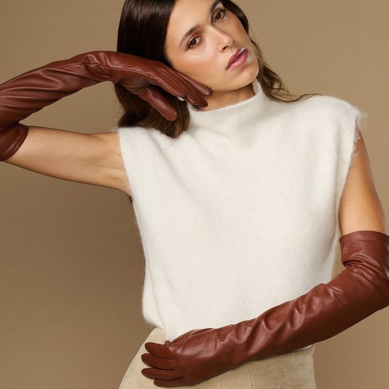 Chestnut brown leather opera gloves with long fingers, posed with arms reaching forward