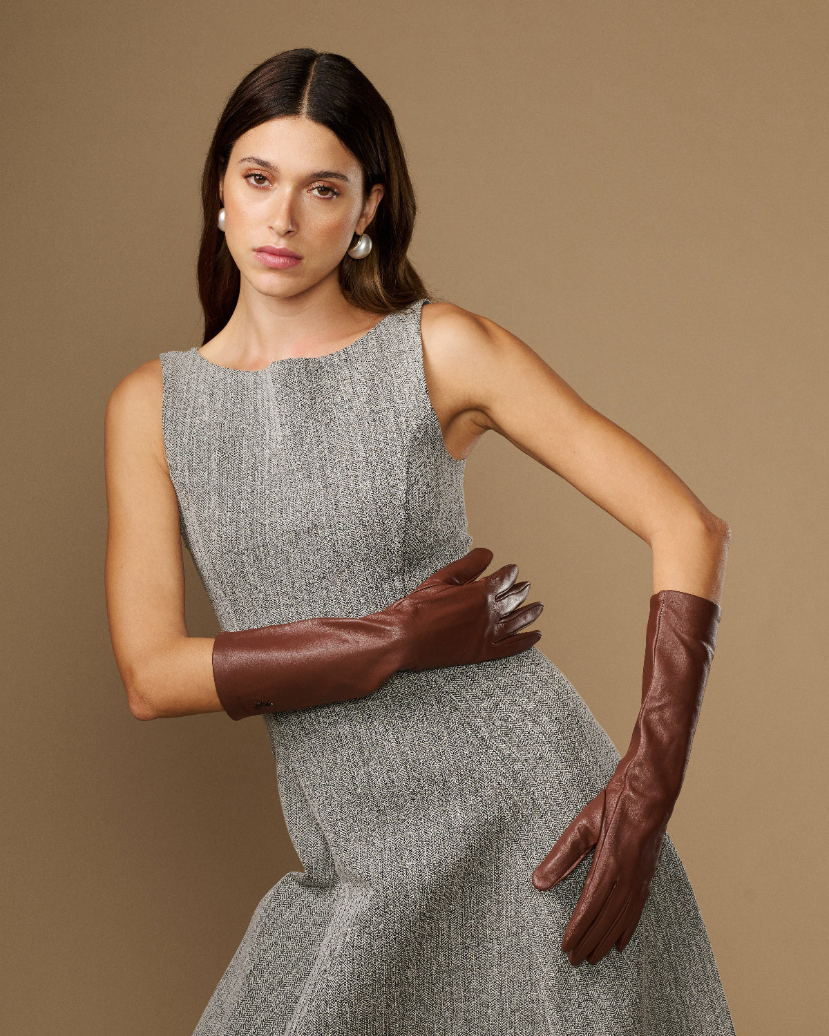 Women's brown below-elbow leather gloves with silk lining, cross-armed pose