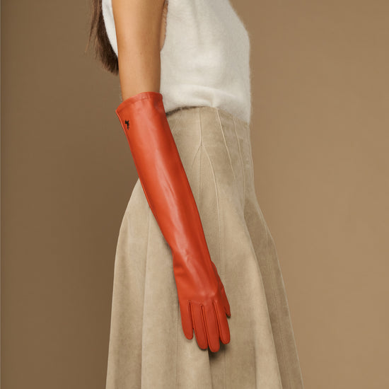 Orange leather elbow-length glove on arm with smooth surface and tapered fingers