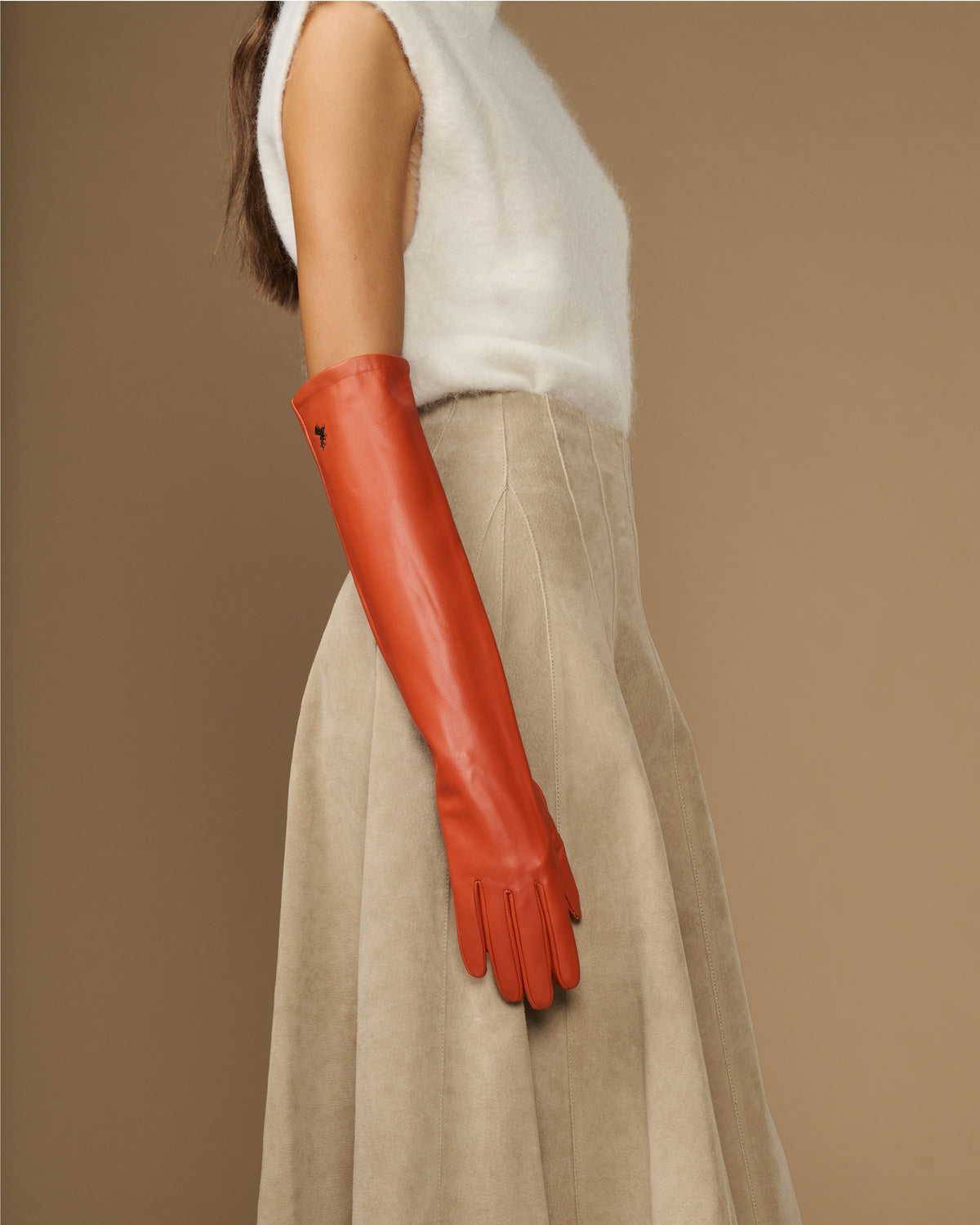 Orange leather elbow-length glove on arm with smooth surface and tapered fingers