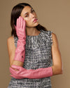 Pink women’s below-elbow leather gloves, smooth finish, hands resting on arms