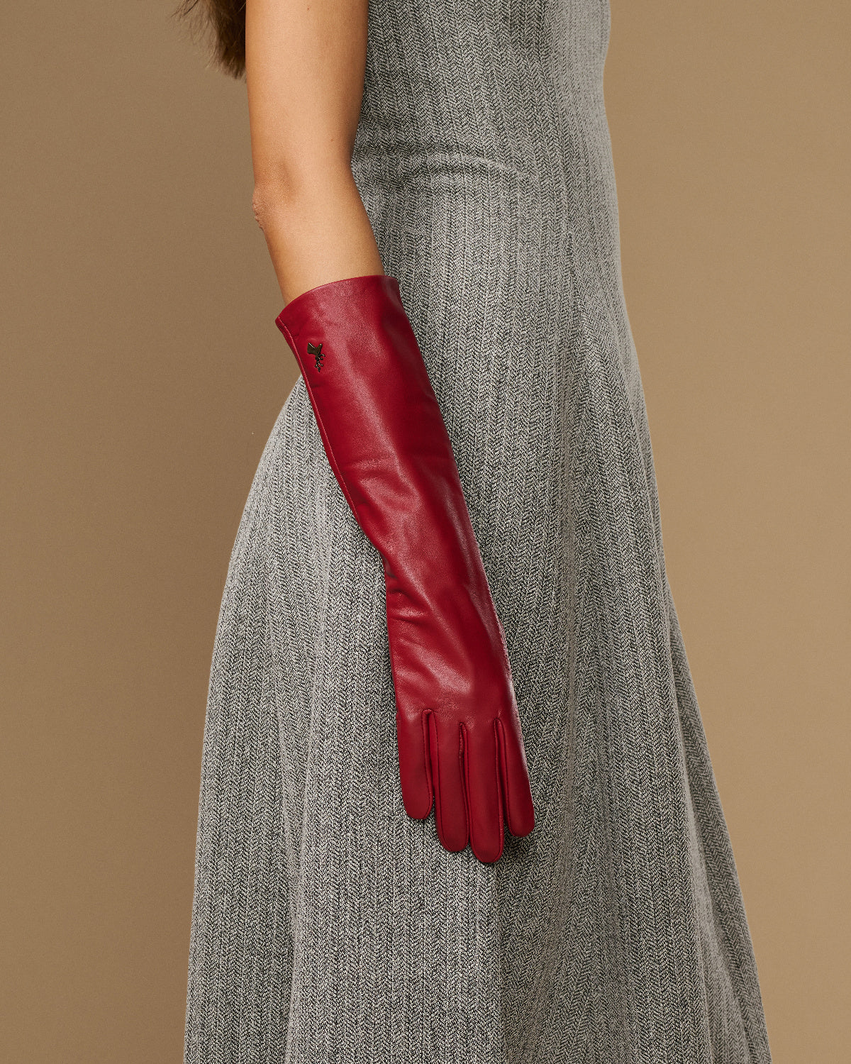 Red leather below-elbow glove on arm, showing long cuff and stitched fingertip seams