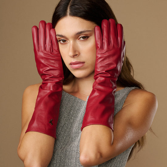 Women’s red leather below-elbow gloves covering hands and wrists, centered portrait view