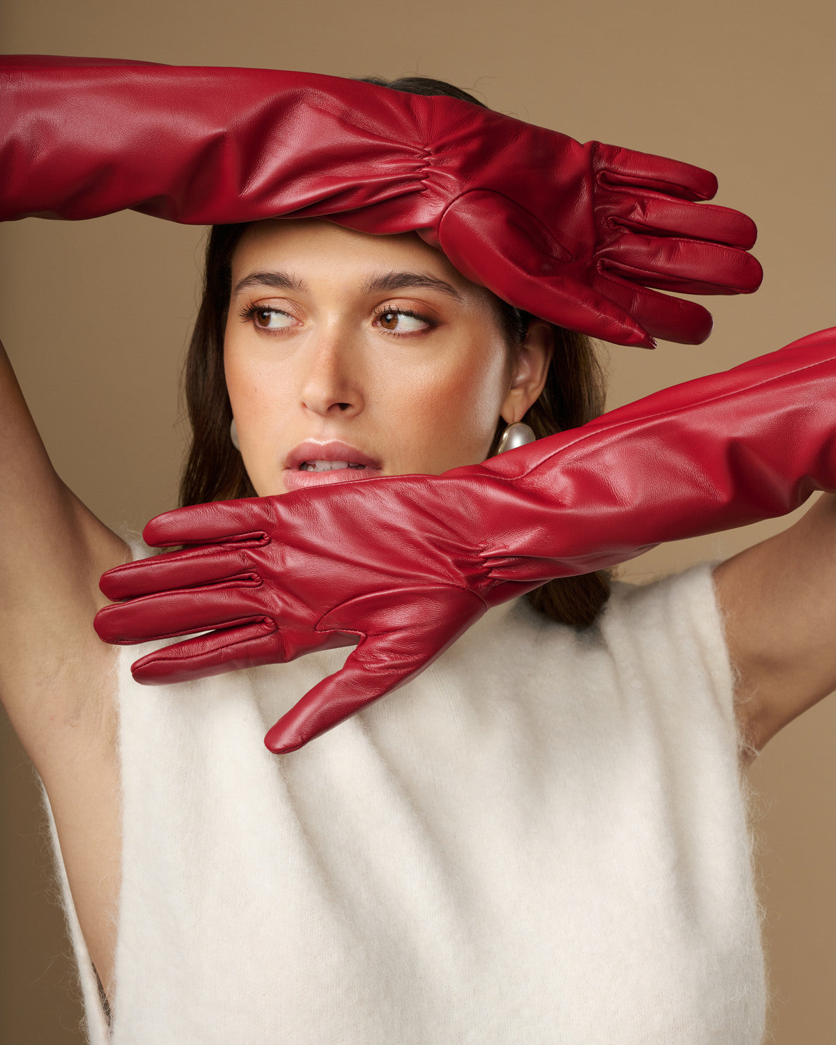 Red leather elbow gloves covering wrists, close-up on glove texture