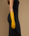 Yellow leather below-elbow glove sleeve with textured sheen and long fingers