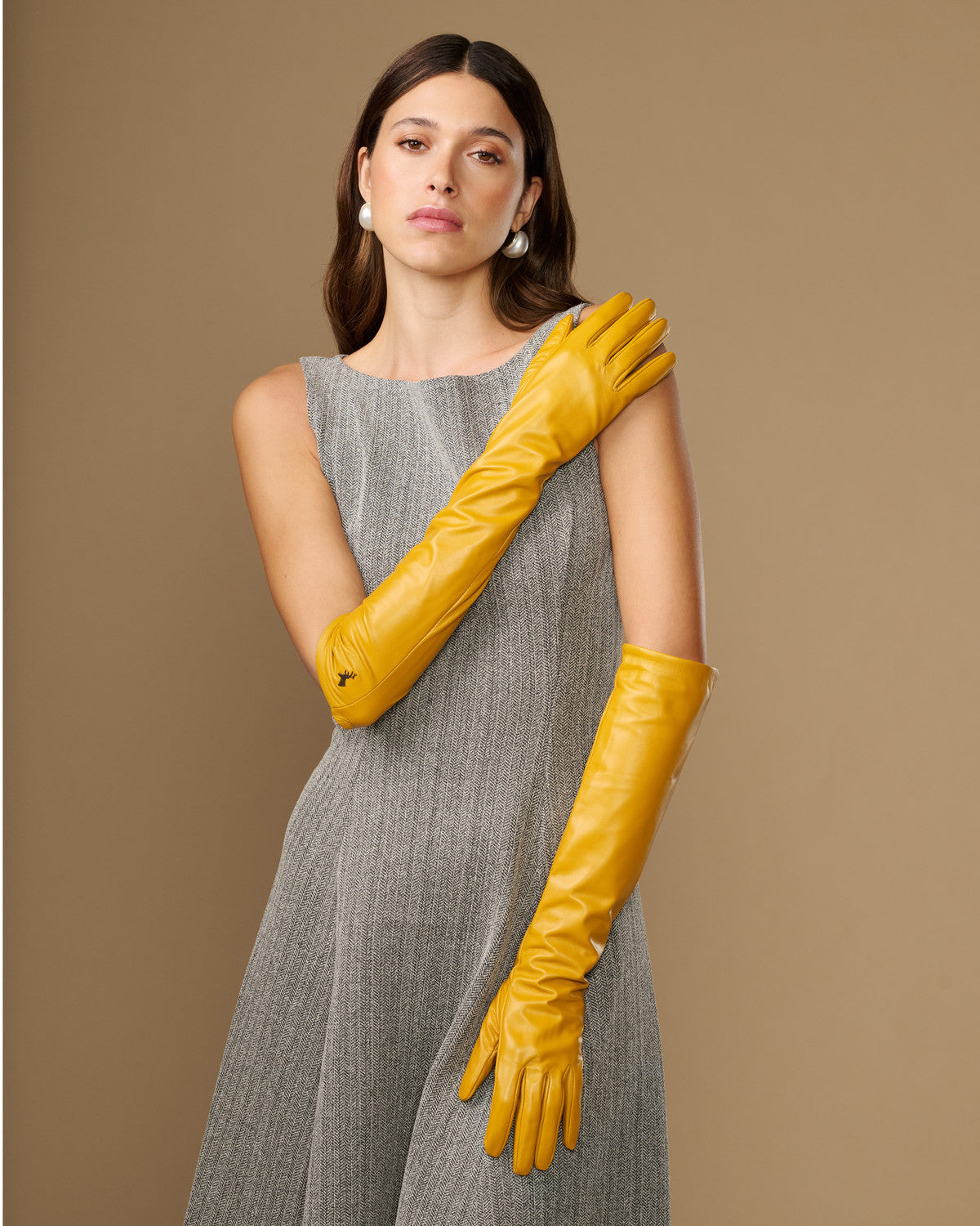 Yellow leather elbow-length gloves with smooth finish and pointed logo on wrist
