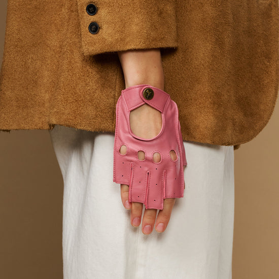 Pink fingerless driving gloves shown from front with snap strap and button accents