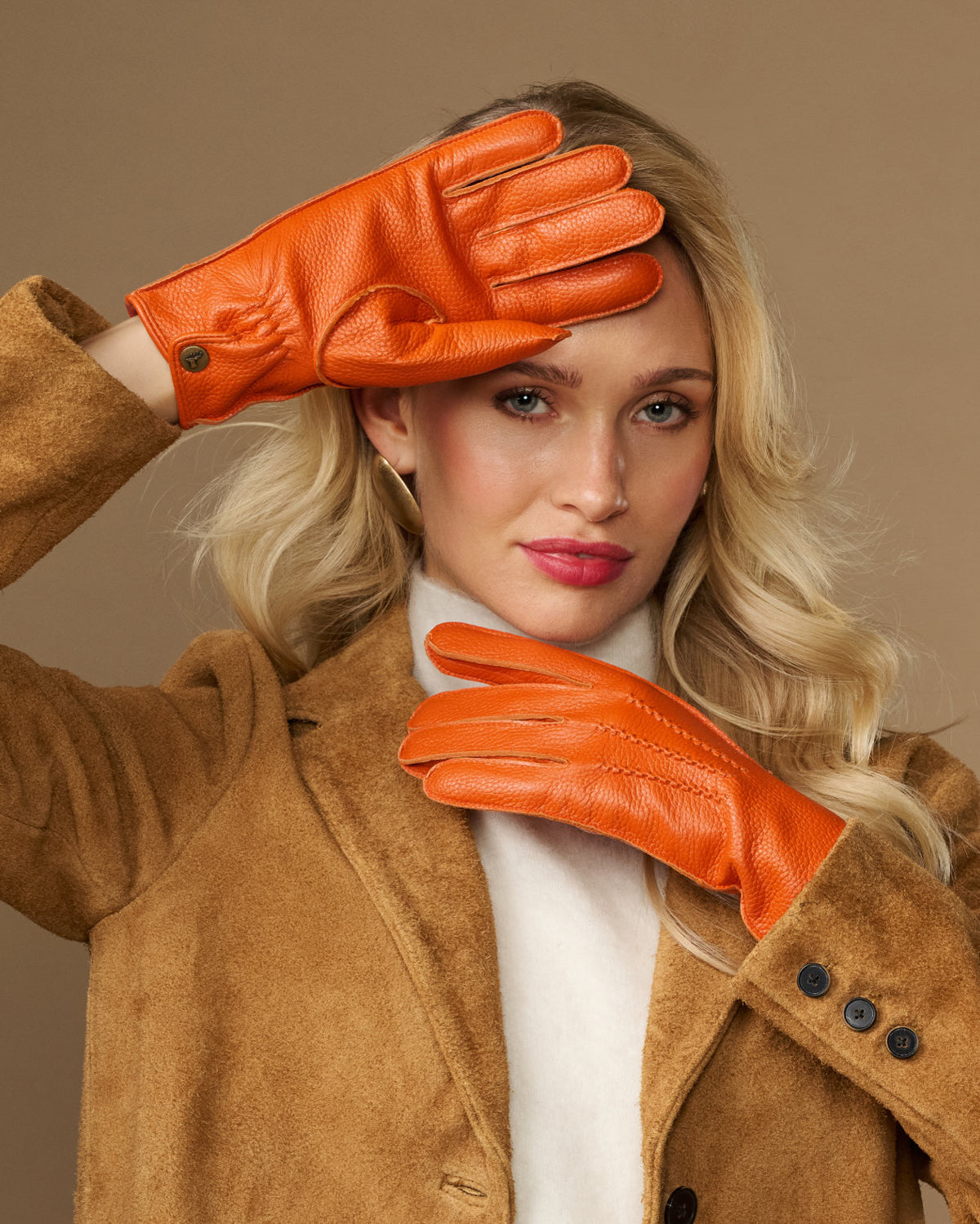 Orange leather deerskin gloves with stitched fingers and soft cuff lining, worn on hands