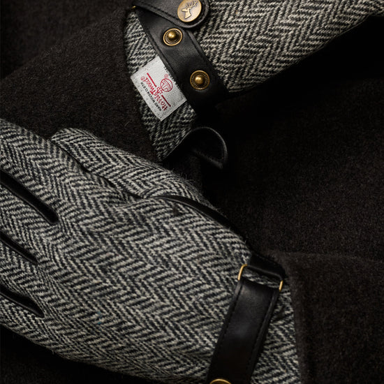 Men's gloves close-up: black leather cuff with gold snaps and gray herringbone panel.