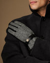 Men's gloves close-up: gray herringbone palm with black leather strap at the wrist.