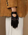 Black leather glove with oval emblem at wrist and studded finger panels.